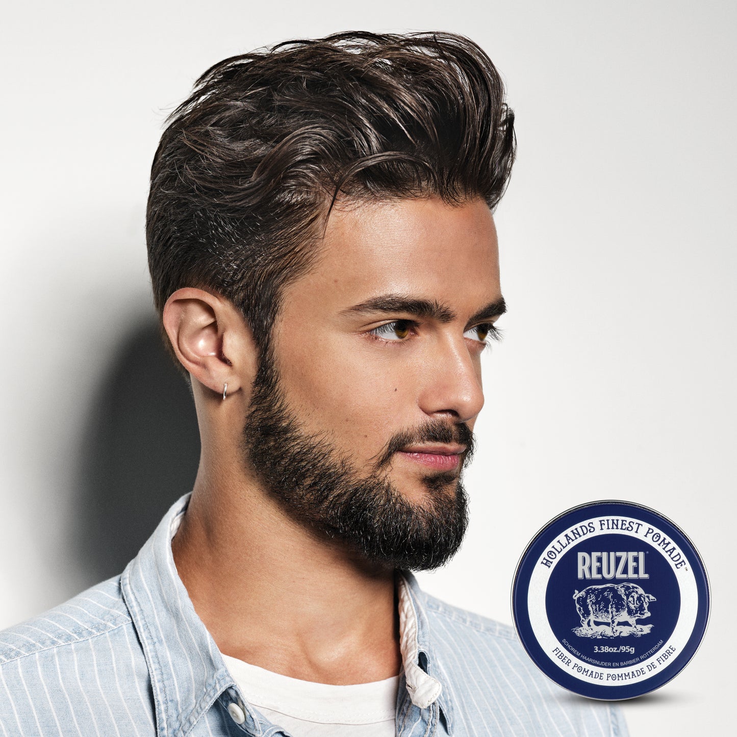 Man with styled hair and beard, hair styled with Reuzel Fiber Pomade. Reuzel logo in the corner