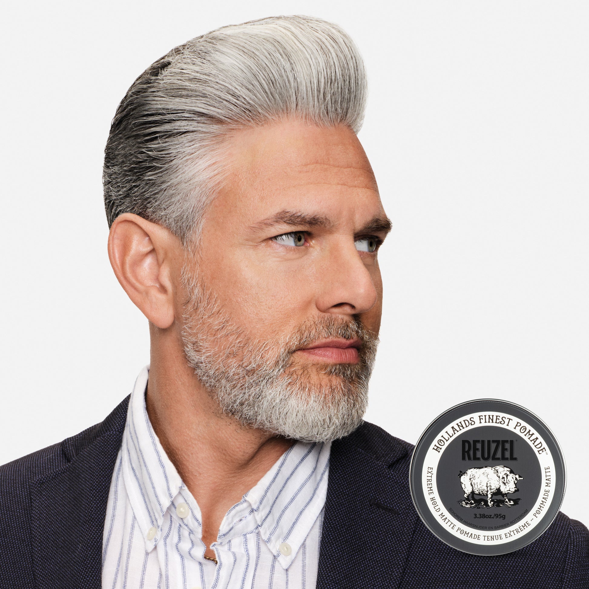 Man with hair styled with Reuzel Extreme Hold Matte Pomade, with a beard wearing a suit, with Reuzel pomade logo.